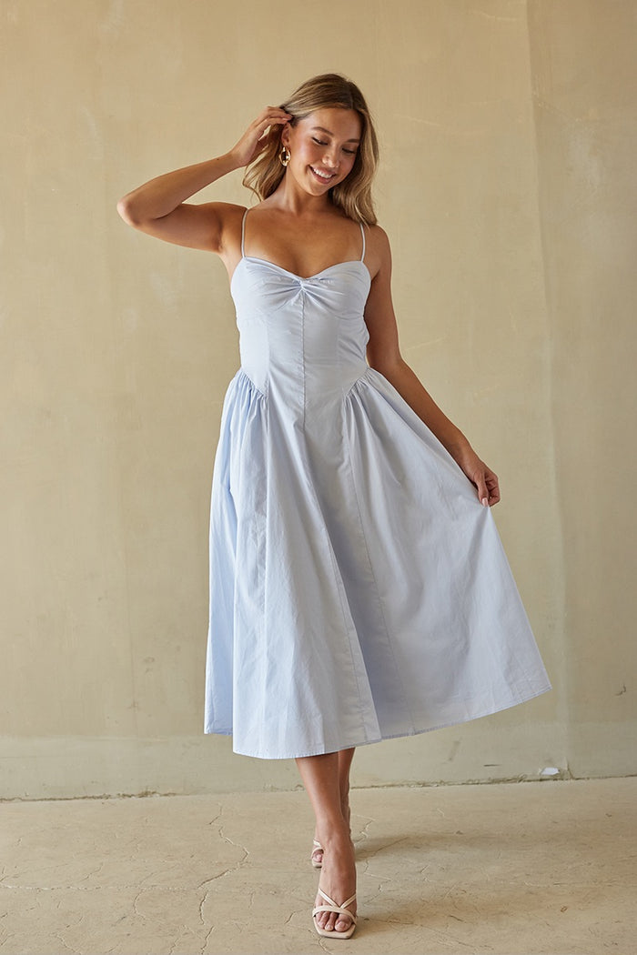 Woman wearing a light blue dress against a beige wall