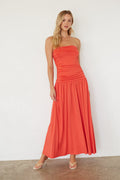 Woman wearing a strapless coral dress against a white background