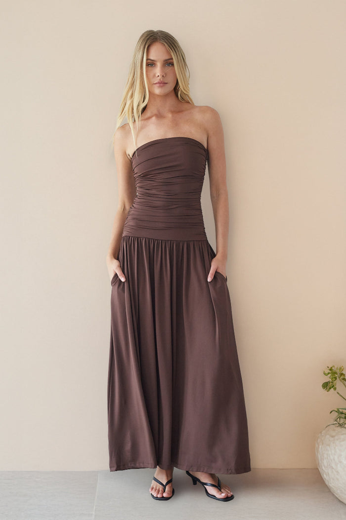brown-image | Woman wearing a strapless brown dress against a plain background