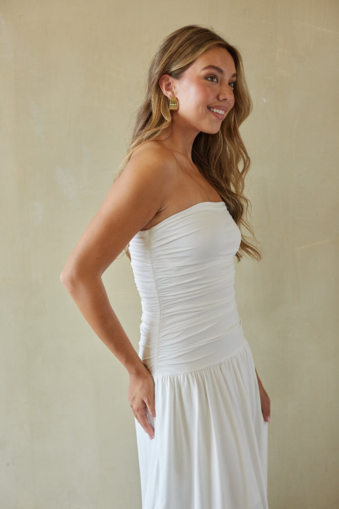 Woman wearing a white strapless dress against a beige background