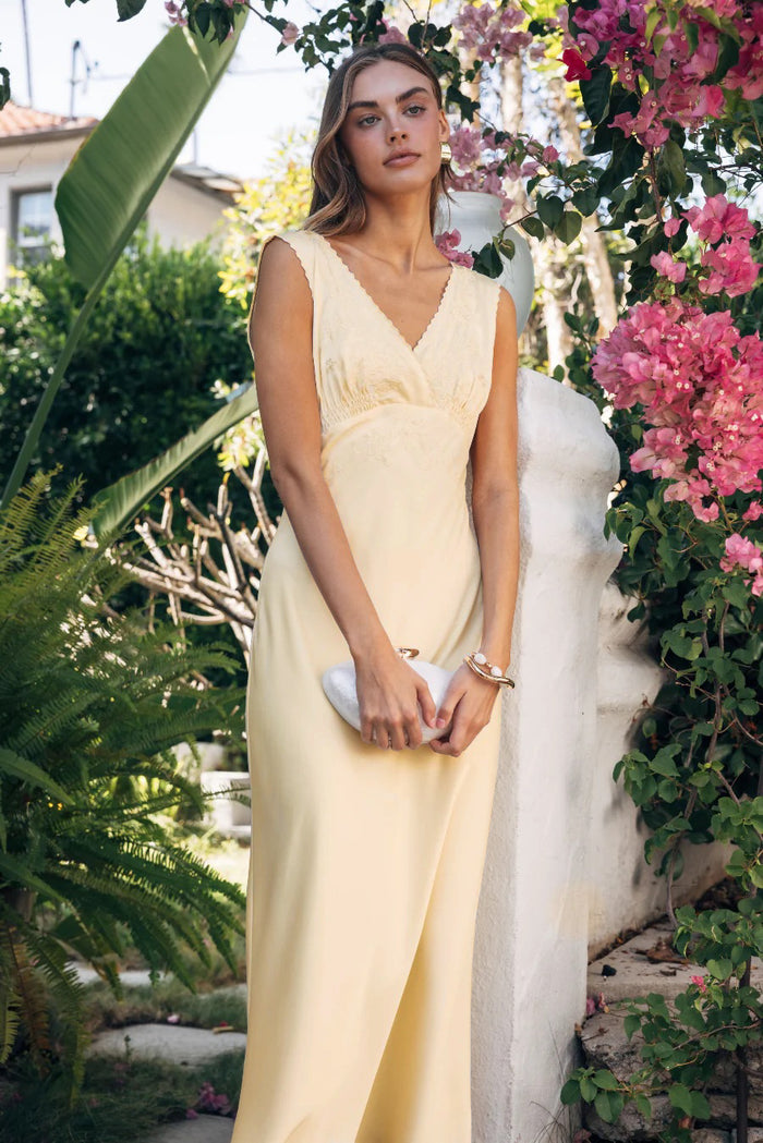 Woman in a white dress standing among flowers and greenery