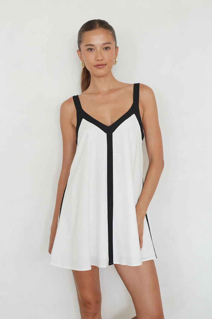 white-image | Woman wearing a white dress with black accents on a plain background