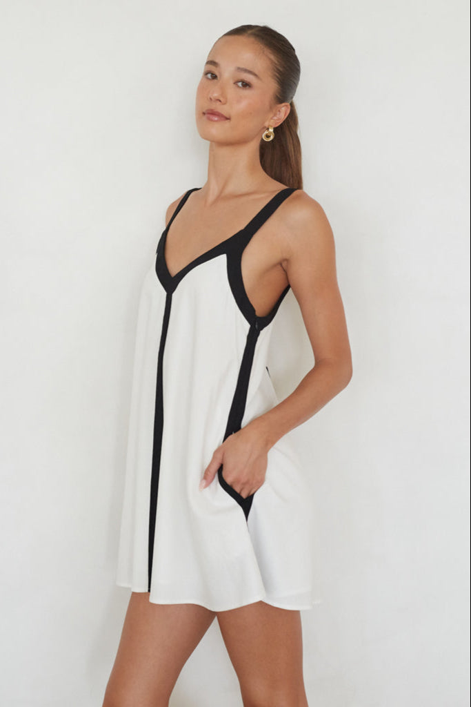 Woman wearing a white and black dress against a plain background