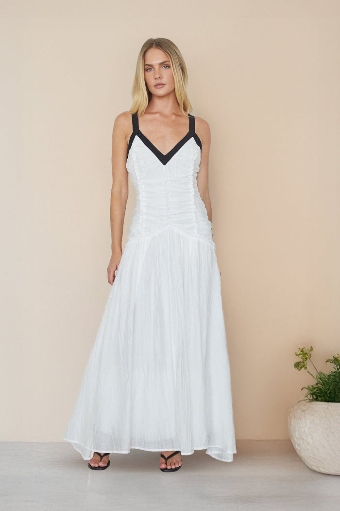 white-image | Woman wearing a white dress with black straps against a beige background