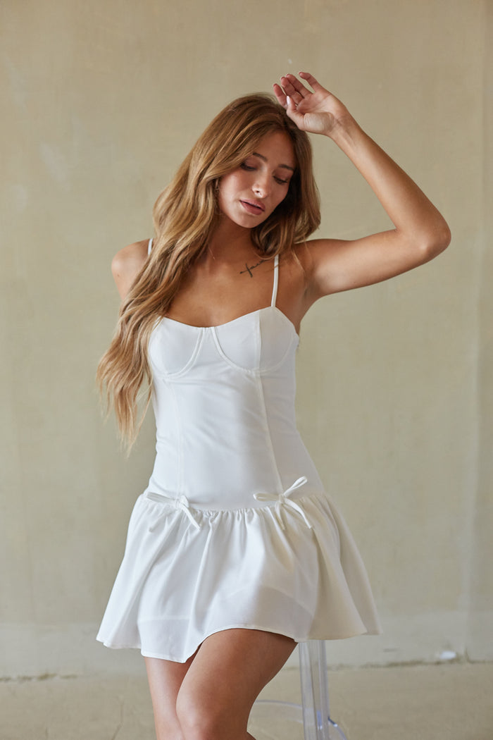 sitting-image | white flared dress | relaxed charm | sitting pose showing the flow of the fabric and bow ties, ideal for lounging in style.