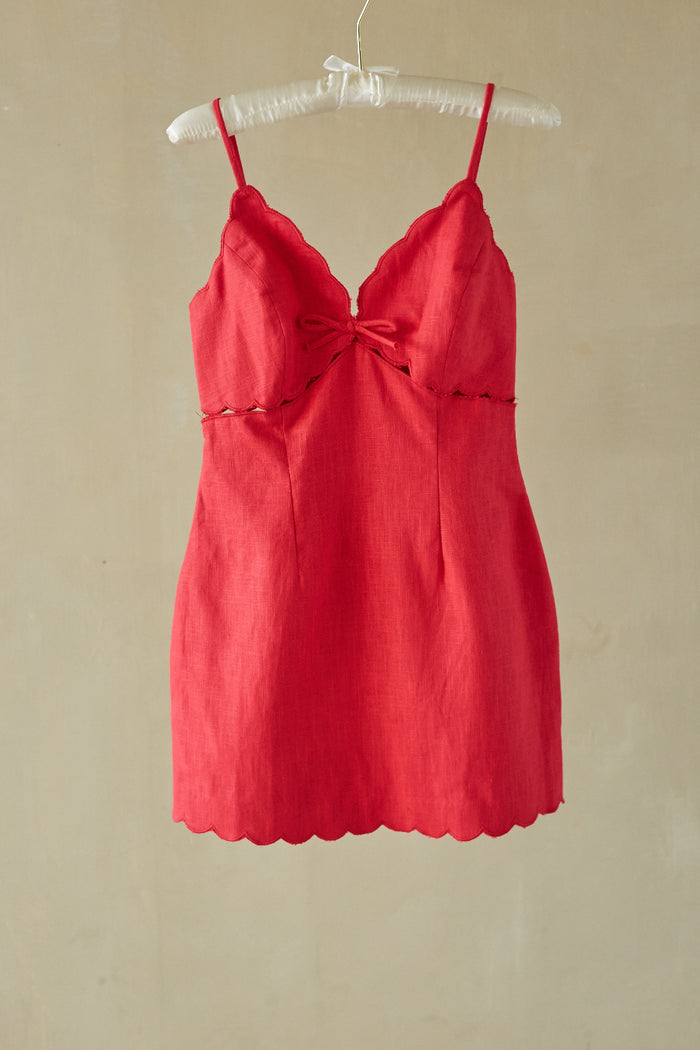 red-image | Red dress on a hanger against a beige wall