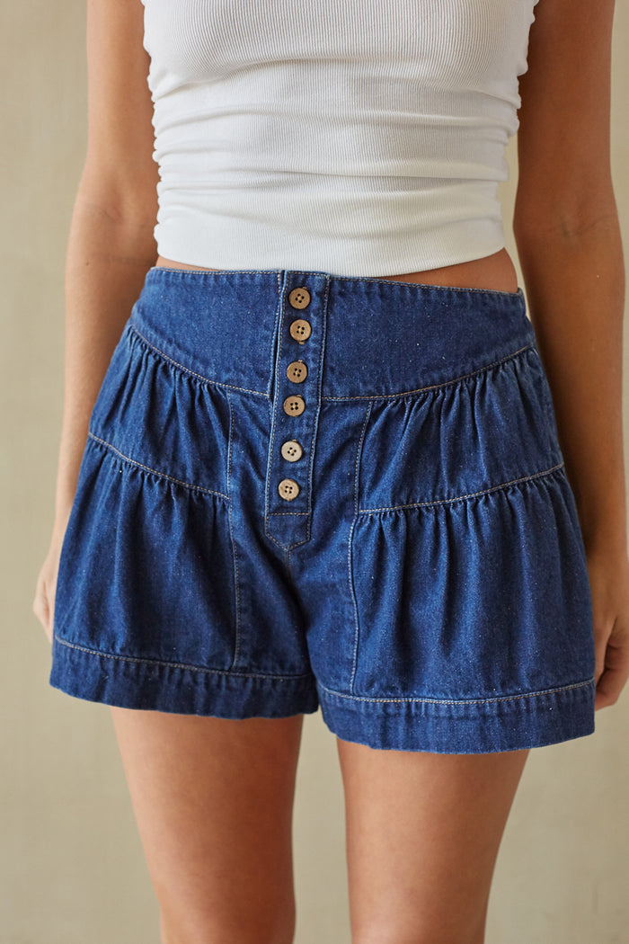 detail-image | denim button-up skirt | a close-up of the skirt’s buttoned waistband and tiered design, focusing on the texture of the denim