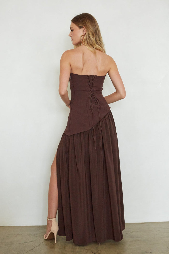 Woman wearing a brown strapless dress with a slit on a white background