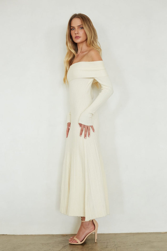 Woman wearing a white off-shoulder dress against a plain background