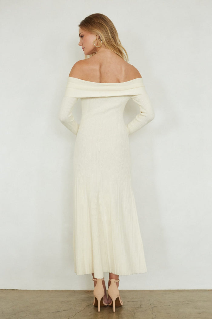 Woman wearing a white off-shoulder dress against a plain background
