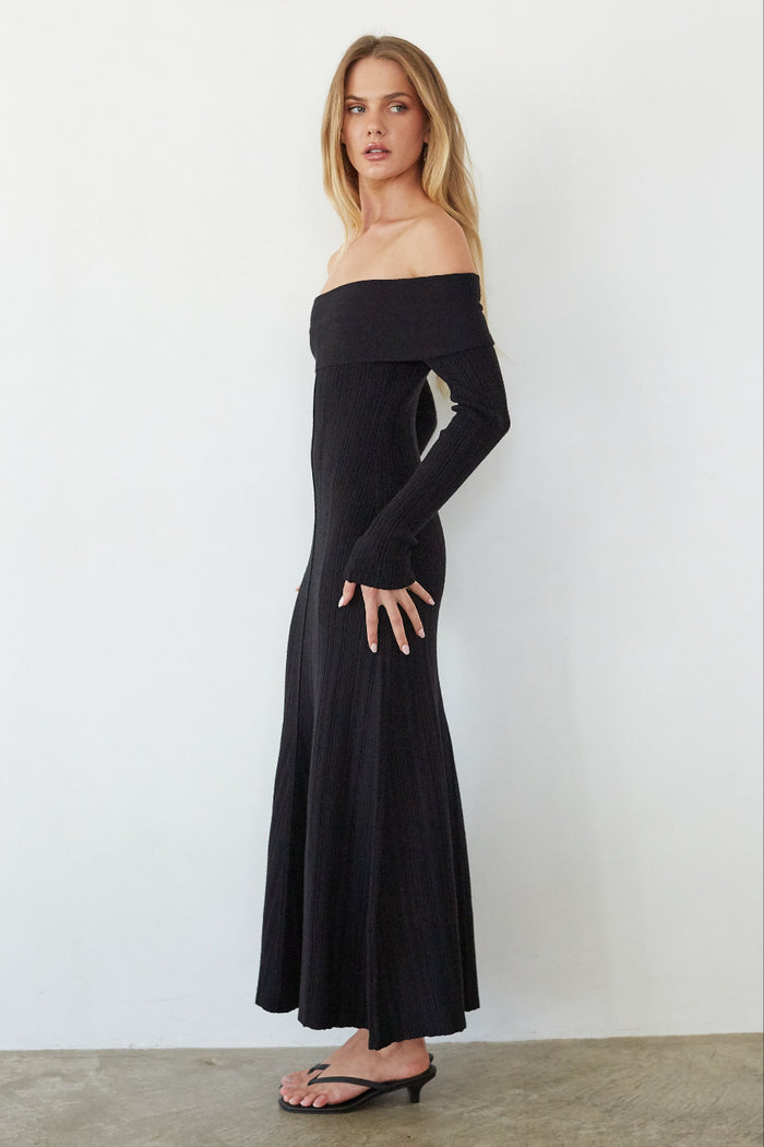Woman wearing a black off-shoulder dress against a white background