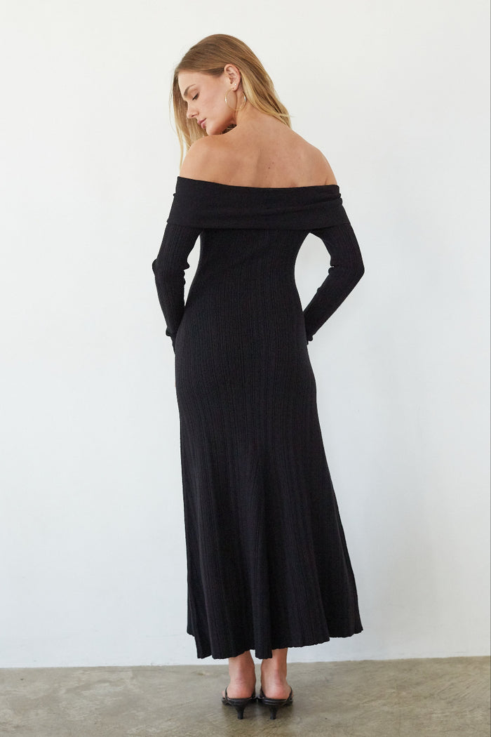 Woman wearing a black off-shoulder dress against a white background