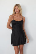 Woman wearing a black slip dress against a white background