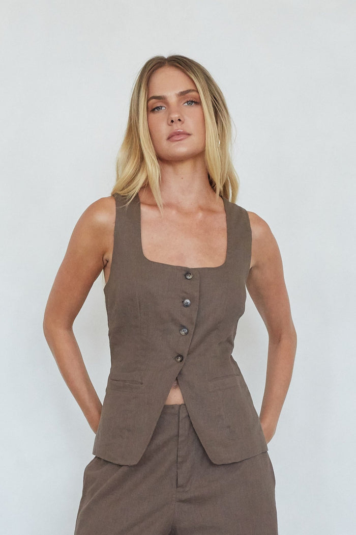 Woman wearing a brown vest and pants against a white background