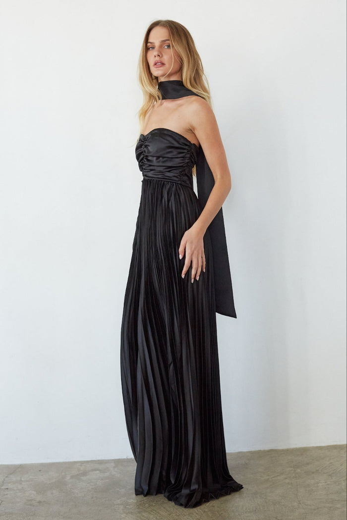 Woman wearing a black strapless gown against a white background