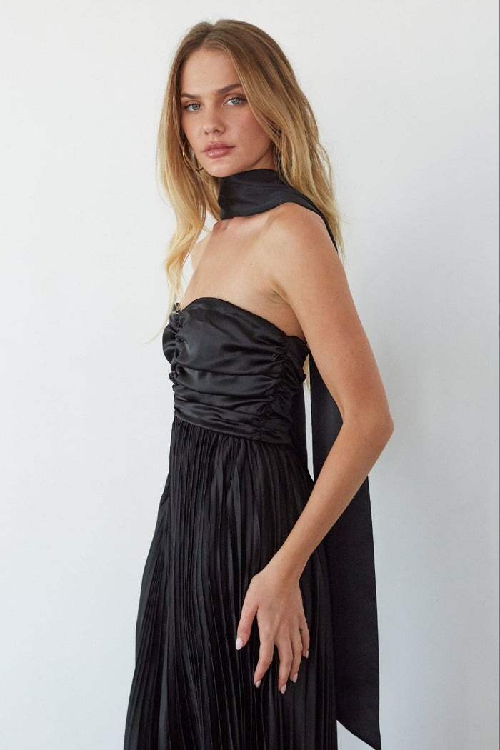 Woman wearing a black strapless dress against a white background