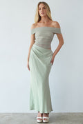 Woman wearing a light green off-shoulder top and skirt set against a white background