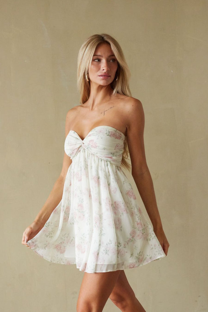 Woman wearing a white floral dress against a beige background