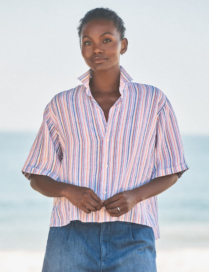 Person wearing a striped shirt and blue pants against a light background