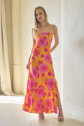 Woman wearing a yellow floral dress standing in a softly lit room.