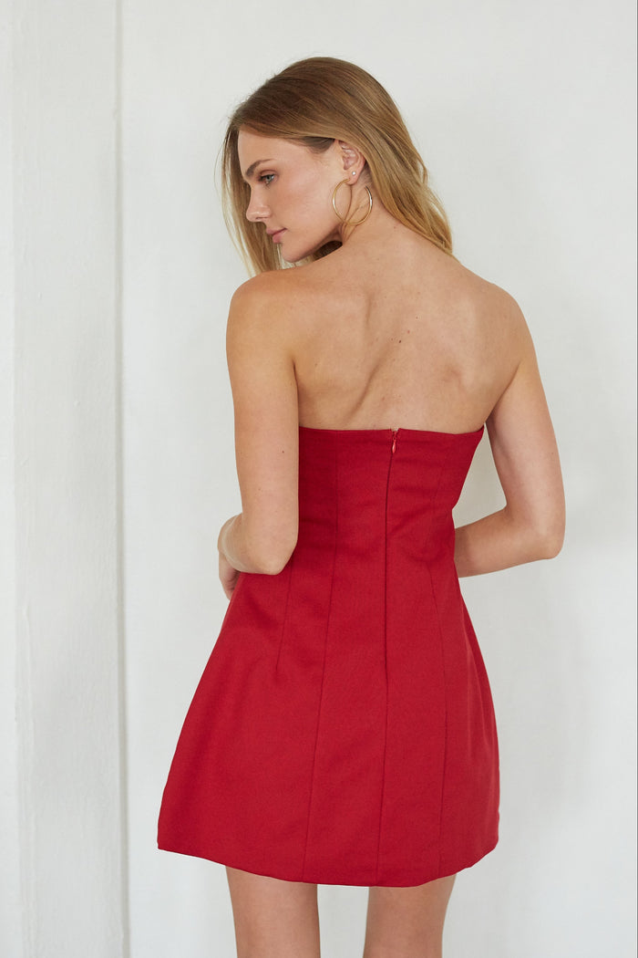 Woman wearing a strapless red dress against a white background