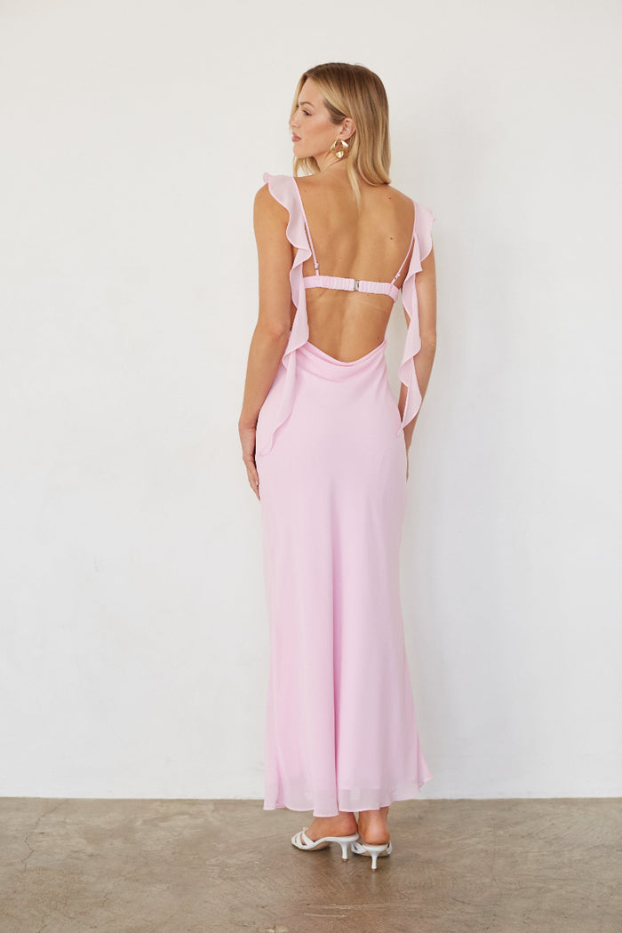 Woman wearing a pink dress with a backless design on a white background