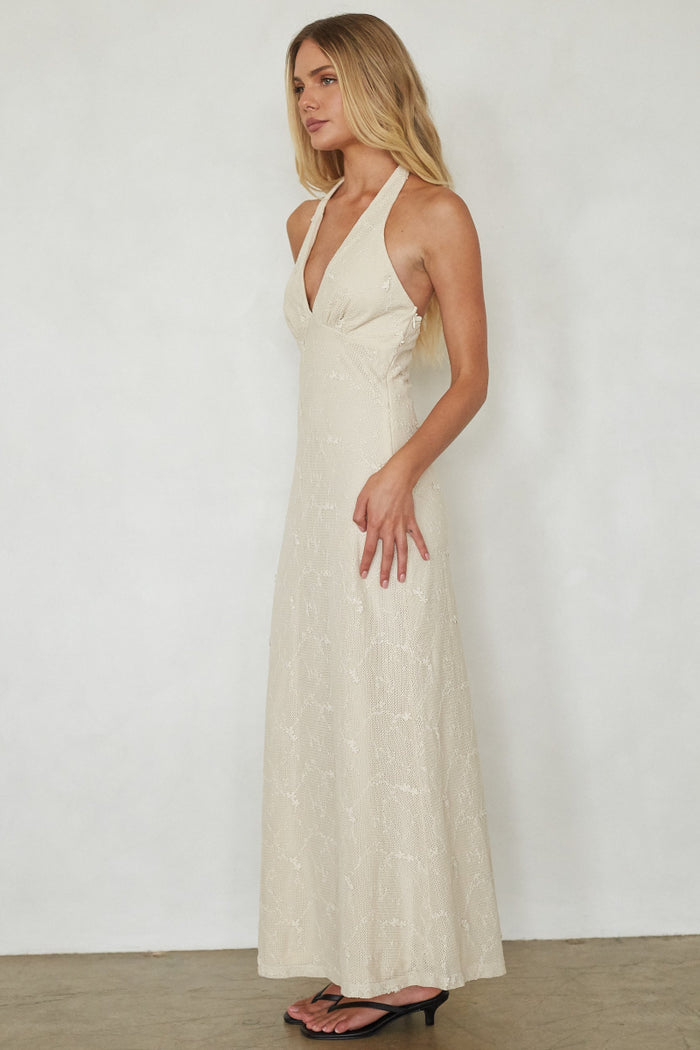 Woman wearing a beige halter neck dress against a white background