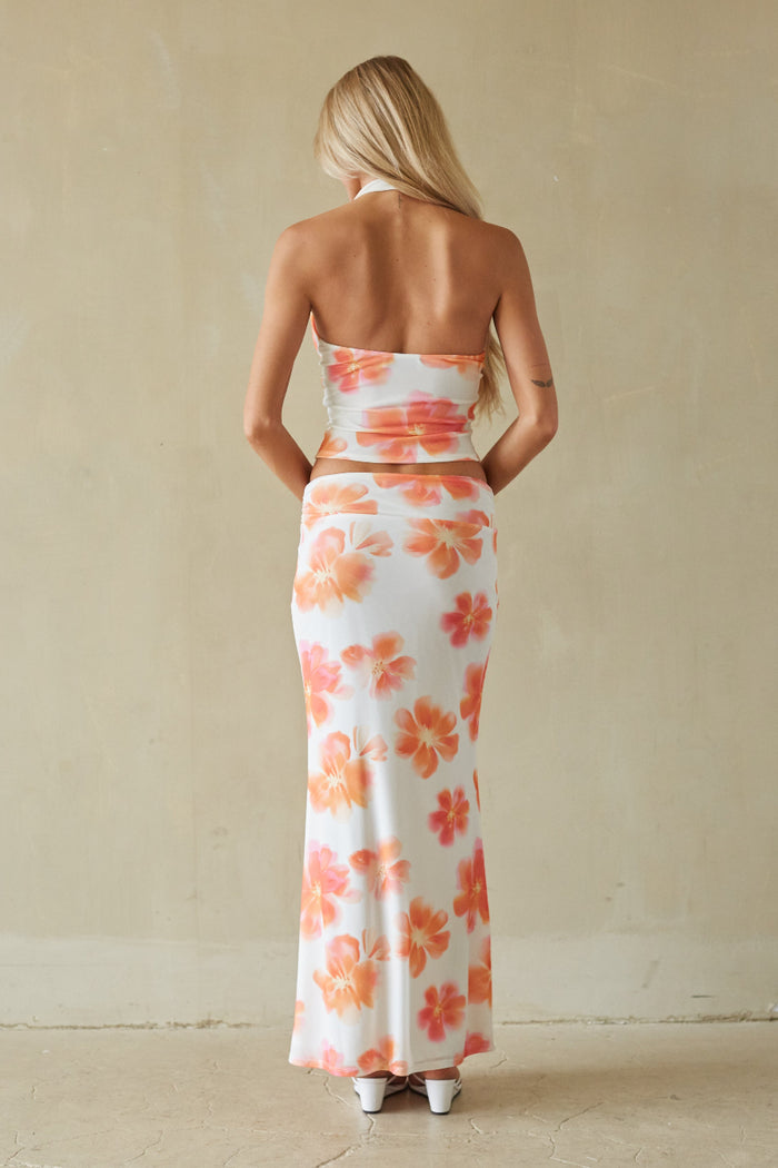Woman wearing a strapless floral dress against a beige wall.