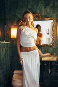 Woman in a white outfit standing in a bathroom with green tiled walls and vintage mirror.