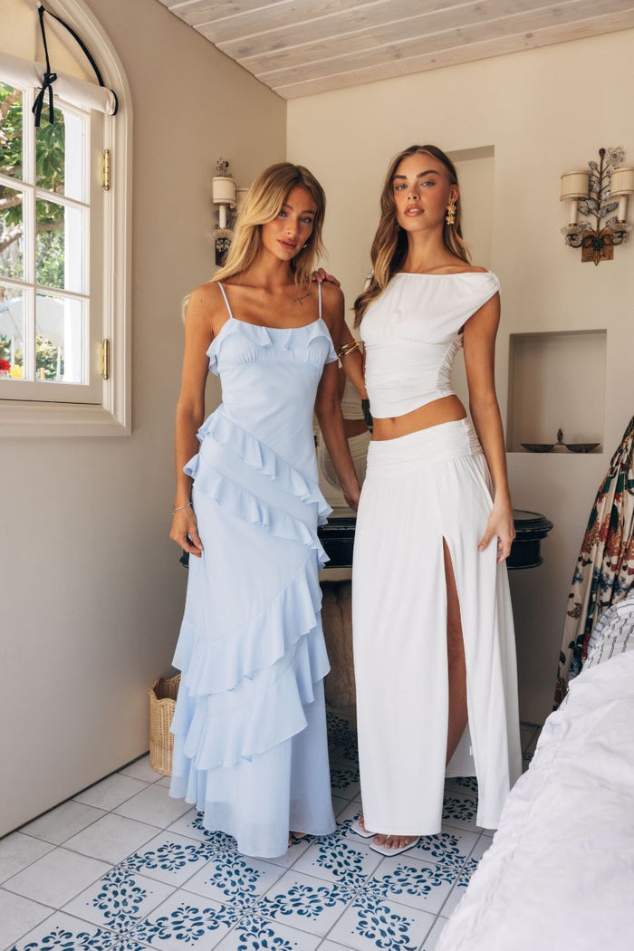 Two women in light blue and white dresses standing in a room with a decorative floor.