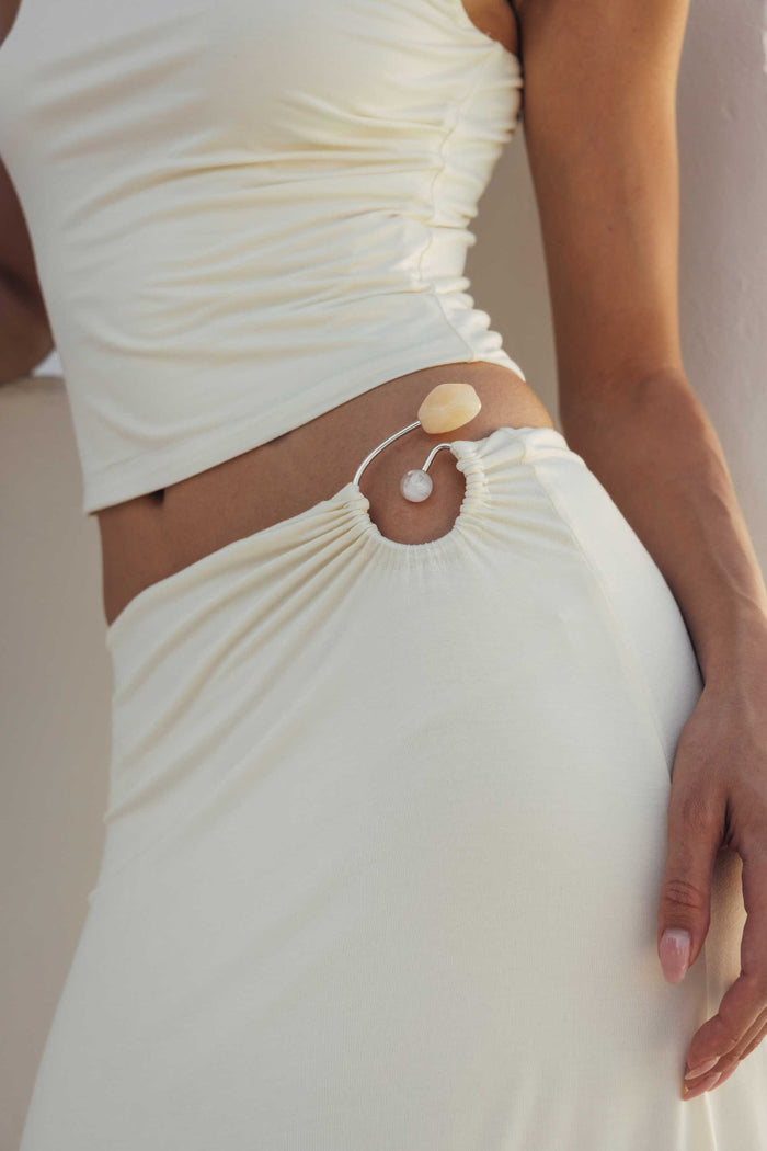 Close-up of a person wearing a white top and skirt with decorative elements.