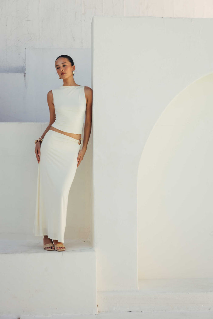 Woman in a white outfit standing against a white wall