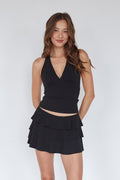 Woman wearing a black halter top and layered skirt against a white background