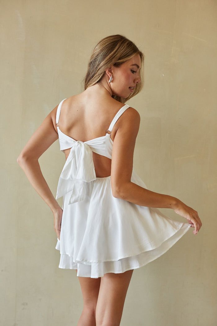 Woman wearing a white dress with a beige background