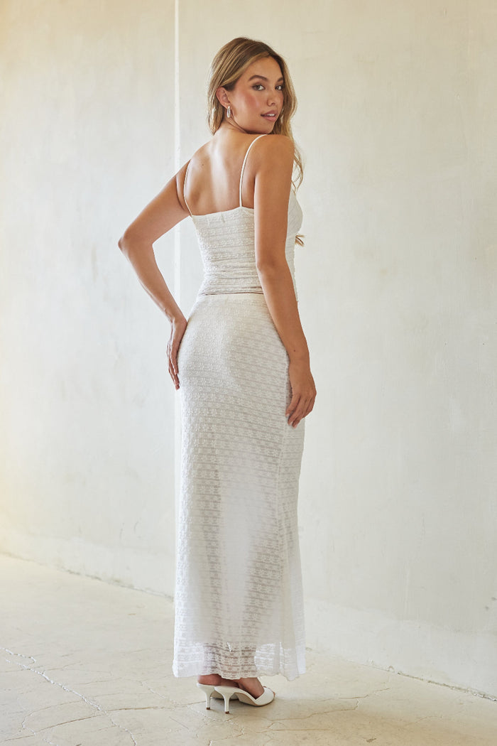 Woman wearing a white lace dress against a plain background
