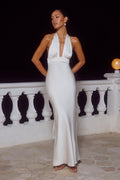 white-image | Woman in a white halter neck gown standing on a stone patio with a dark background