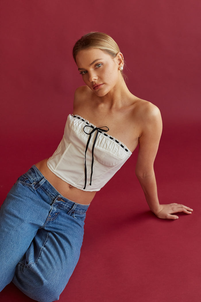 white corset top with black contrast ribbon detail on bodice and ruched detailing along bust | coquette aesthetic white and black ribbon top | white and black lace top | white corset for spring