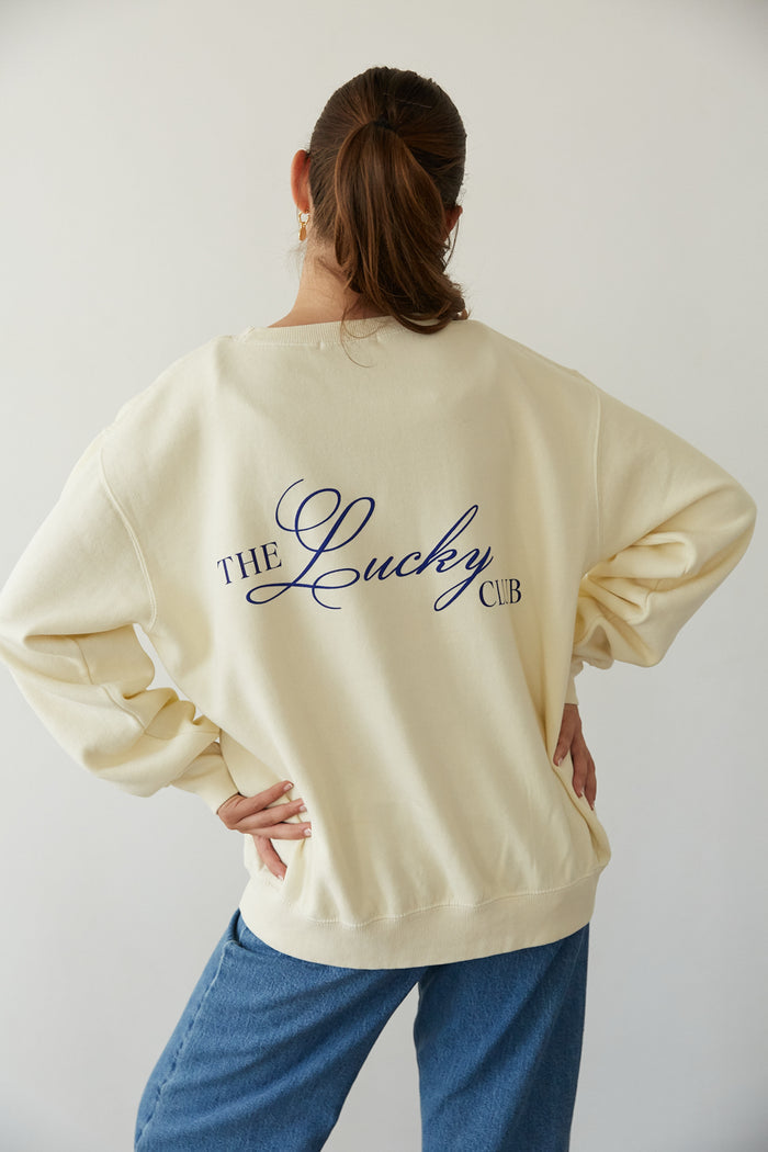 back view | butter yellow cozy crewneck that says The Lucky Club in Cobalt Blue with 777 Pocket detail