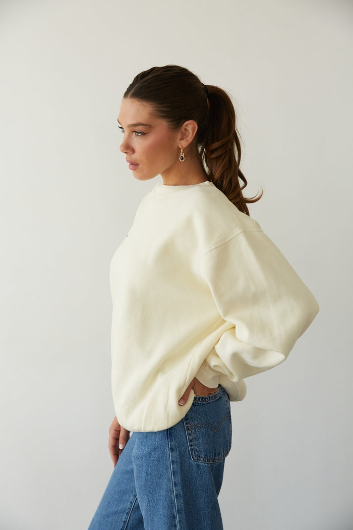 side view | butter yellow cozy crewneck that says The Lucky Club in Cobalt Blue with 777 Pocket detail