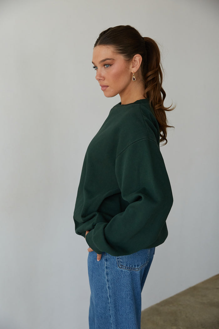 side view | forrest cozy crewneck that says The Sweetheart Department in Peach Pink with Bow Pocket detail