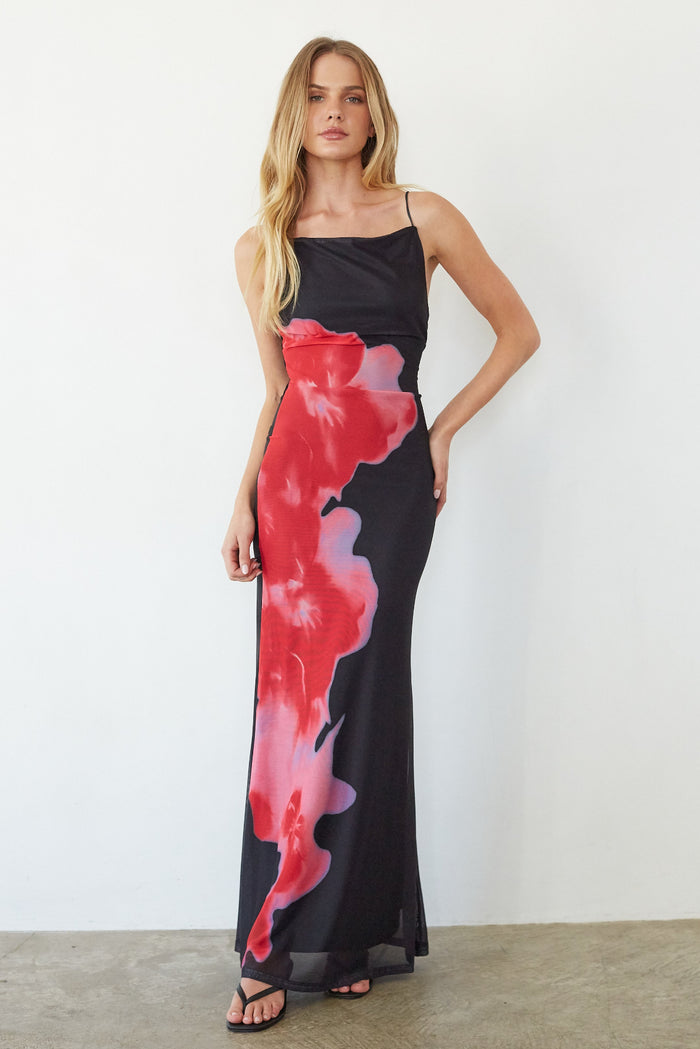 Woman wearing a black dress with red floral patterns against a white background
