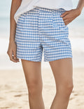 Person wearing blue and white checkered shorts on a beach.