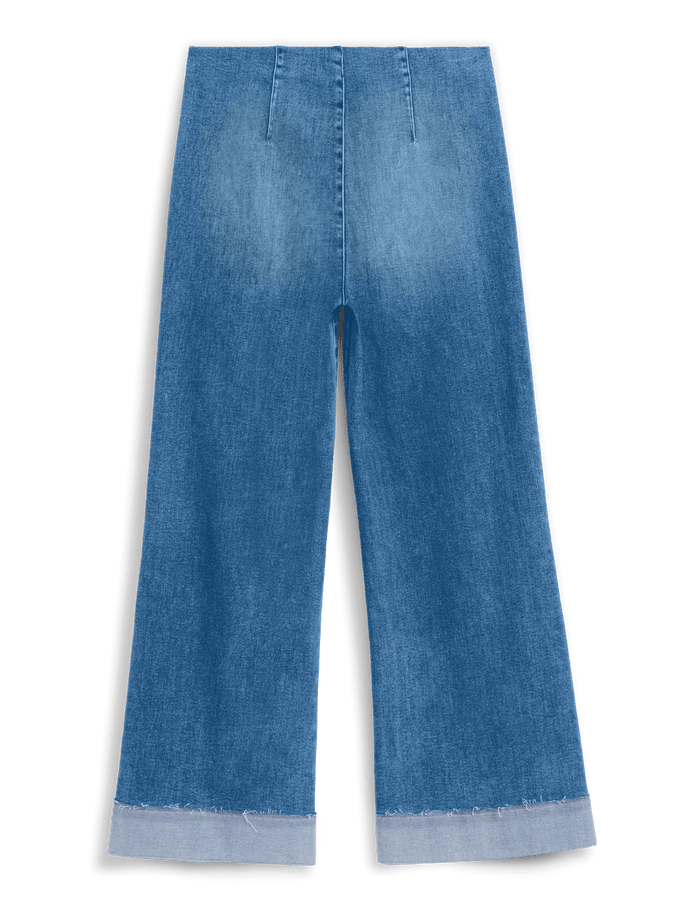 A pair of wide-leg cropped jeans in a medium blue denim wash, featuring a raw, frayed hem, shown against a solid black background.