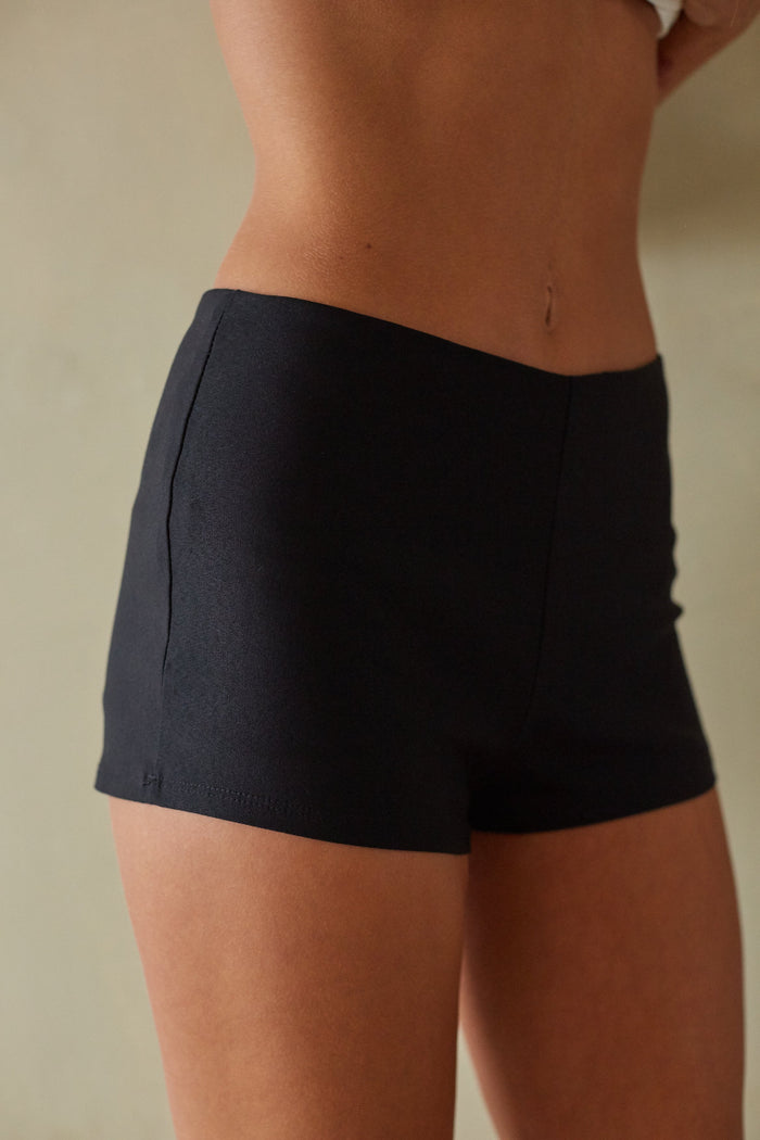 Person wearing black shorts against a neutral background