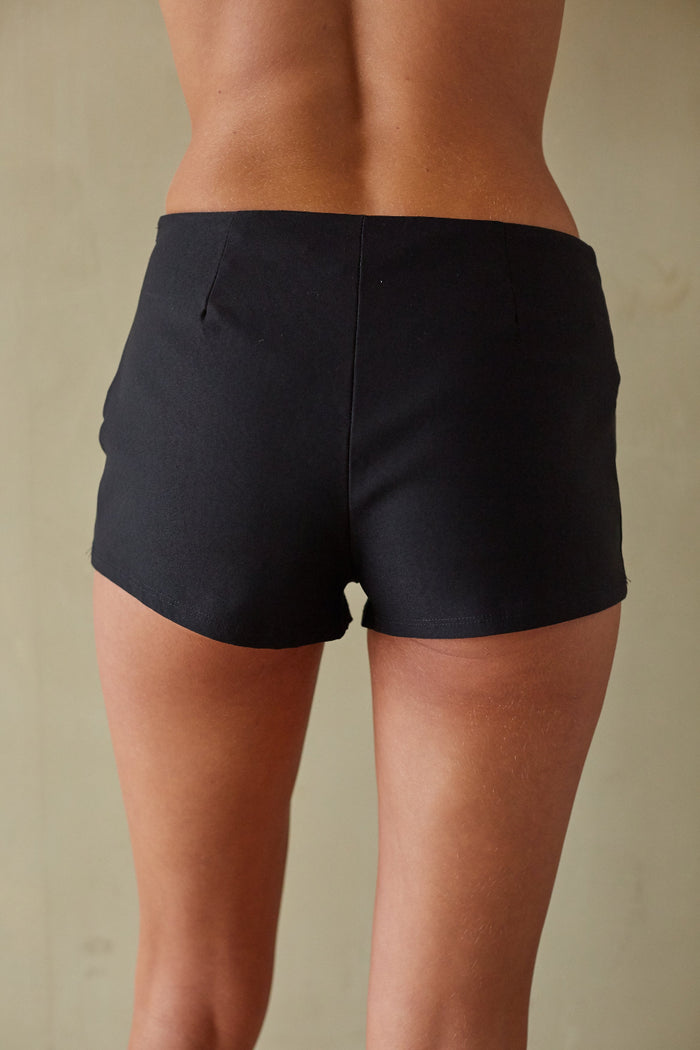 Person wearing black shorts on a beige background