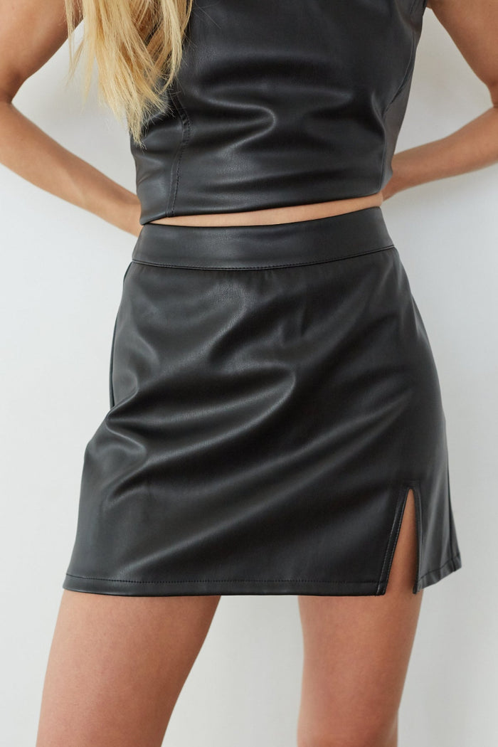 Black leather skirt worn by a person on a white background