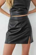 Black leather skirt worn by a person on a white background