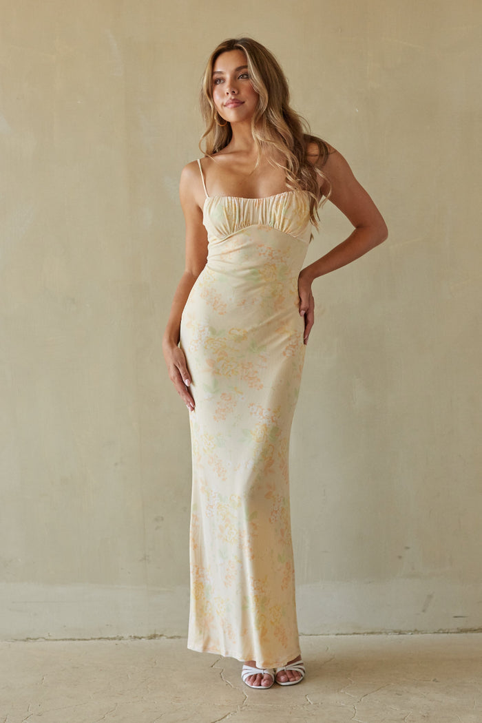 yellow-image | Woman wearing a long, light-colored dress against a plain wall.