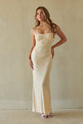 yellow-image | Woman wearing a long, light-colored dress against a plain wall.