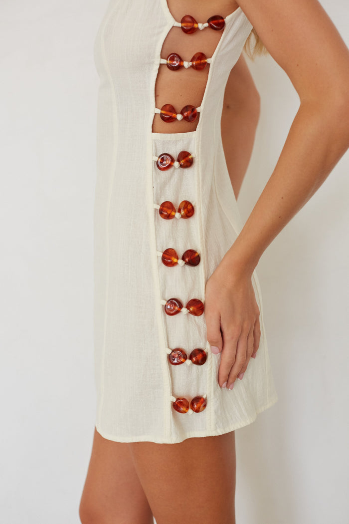 White dress with red button details on a white background